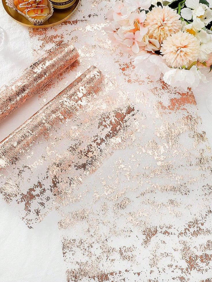 the table is covered with rose gold sequins and pink flowers, along with candles