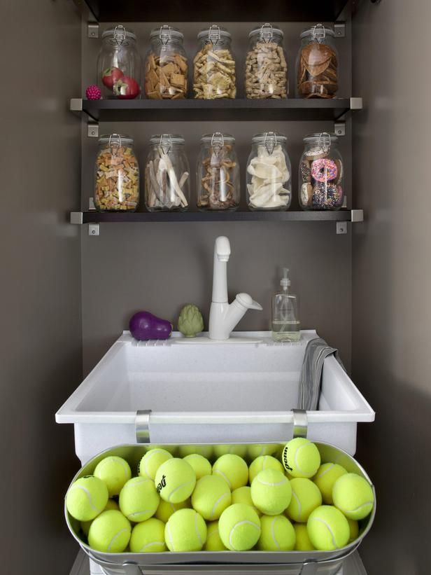 tennis balls are stacked in a bin next to shelves with jars and bottles on them