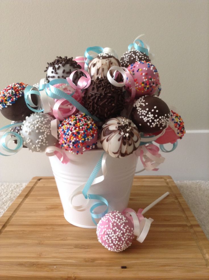 a white vase filled with chocolate covered donuts and sprinkles on top of a wooden table