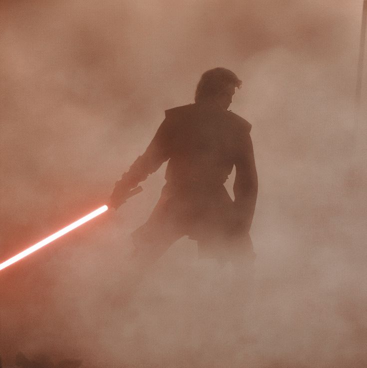 a man with a lightsaben standing in the fog while holding a light saber