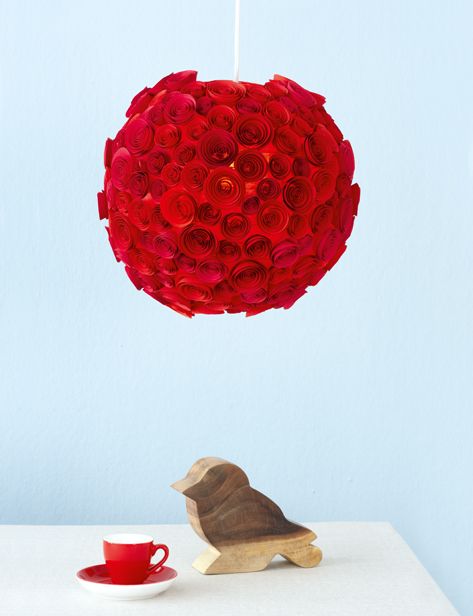 a red rose ball hanging from a string with a dog figurine next to it