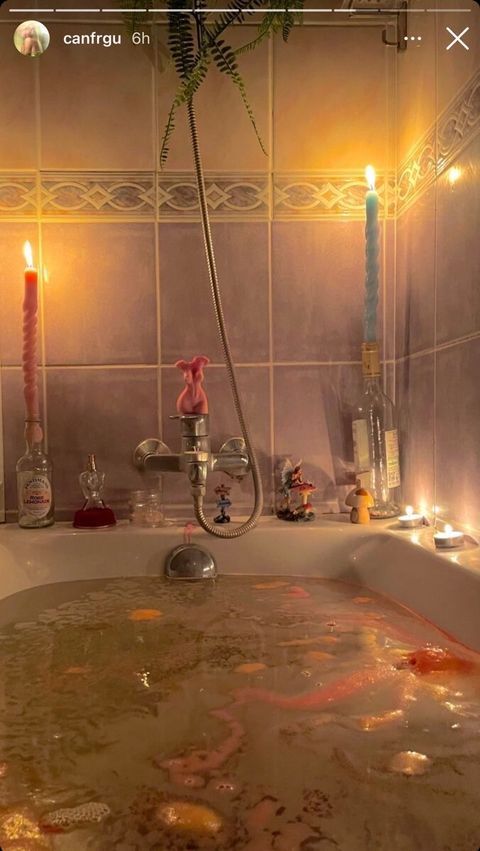 a bathtub filled with lots of water next to two candles and some plants in it