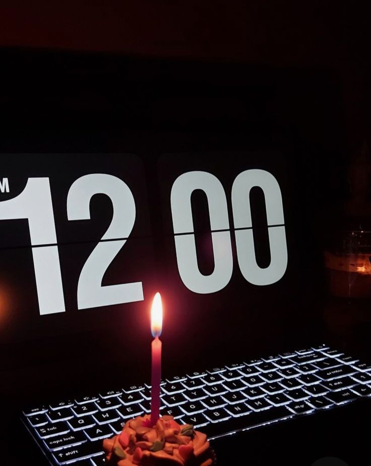 a lit candle sitting on top of a keyboard in front of a sign that reads 120