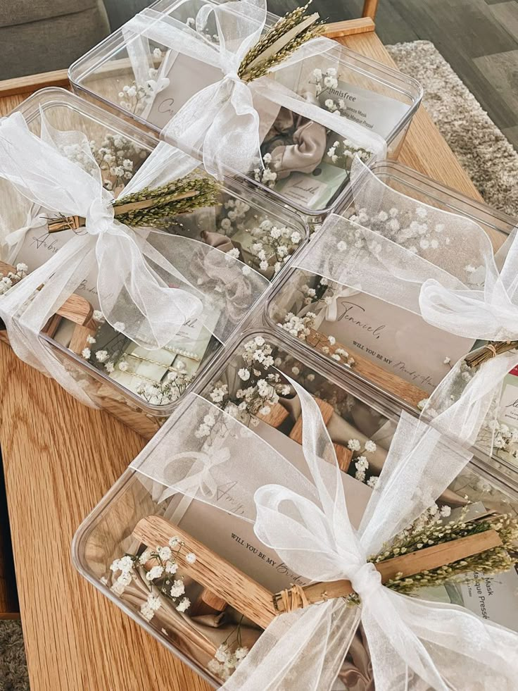 several clear plastic containers filled with flowers and pictures on a table top next to a wooden chair