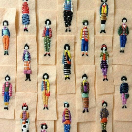 many small handmade dolls are displayed on the wall