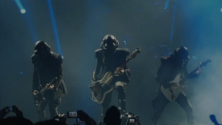 three people with guitars on stage at a concert