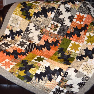 an orange and black quilt sitting on top of a leather chair