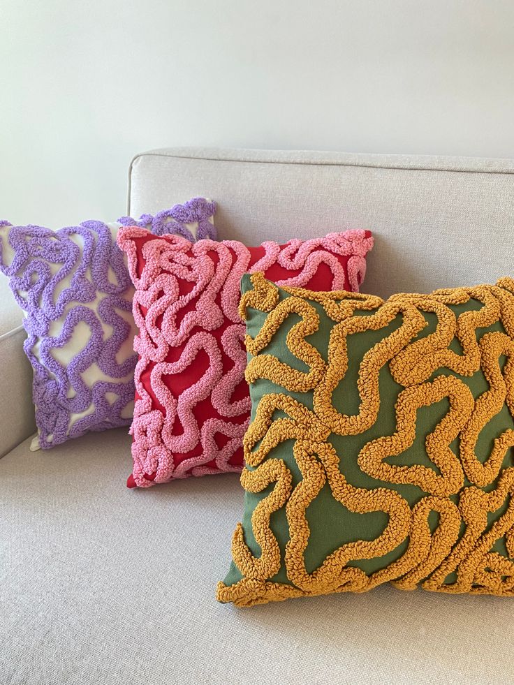 three decorative pillows on a white couch