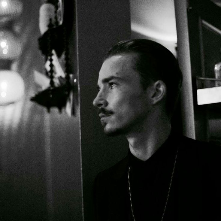 a man standing in front of a mirror wearing a black shirt and silver chain necklace