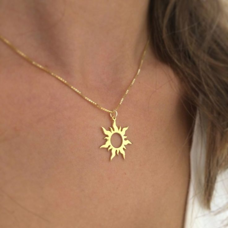 a woman wearing a gold necklace with the sun on it's back and bottom