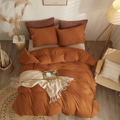 a bed with an orange comforter and pillows