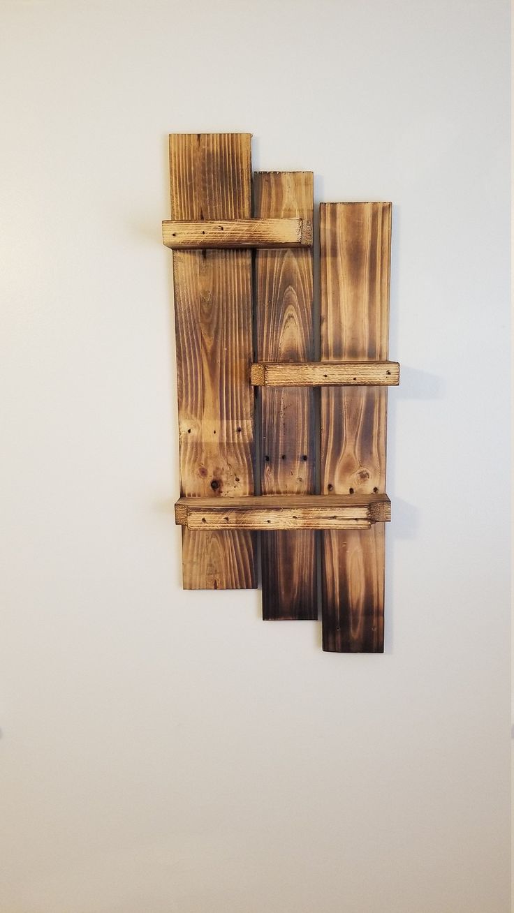 a wooden wall hanging on the side of a white wall