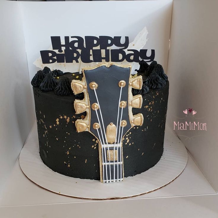 a black and gold guitar birthday cake in a box