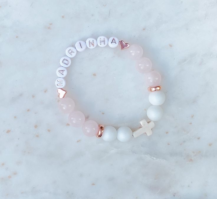 This beautiful personalized beaded bracelet is made with Rose Quartz ( Pink), Aquamarine (Blue) or Alabaster (White),  Howlite Cross and copper beads.   These bracelets are the perfect addition for your special occasion as a favour for a baptism, christening, communion, wedding shower, confirmation or any special or religious occasion.   DETAILS: ♡ Each bracelet comes with letter beads, 10 to 12 - 10MM beads and a Howlite Cross.  ♡ Select bracelet size in drop down.  Custom sizes available, specify in personalization section.  Select size or measure your wrist and add between 1/4 to 1/2 inch depending on your preference. ♡ Made with White Alabaster and Aquamarine or Rose Quartz beads and copper details. ♡ Each bracelet comes packaged beautifully with a jewellery bag. Great as a favour or a Personalized Pink Spiritual Bracelets, Personalized Beaded Bracelets As Gifts, Customizable Pink Charm Bracelet As Gift, Personalized Pink Spiritual Bracelet, Spiritual Personalized Pink Bracelets, Spiritual Pink Personalized Bracelets, Spiritual Personalized Pink Bracelet, Name Beaded Bracelets For Birthday And Mother's Day, Customizable Beaded Bracelets For Birthday