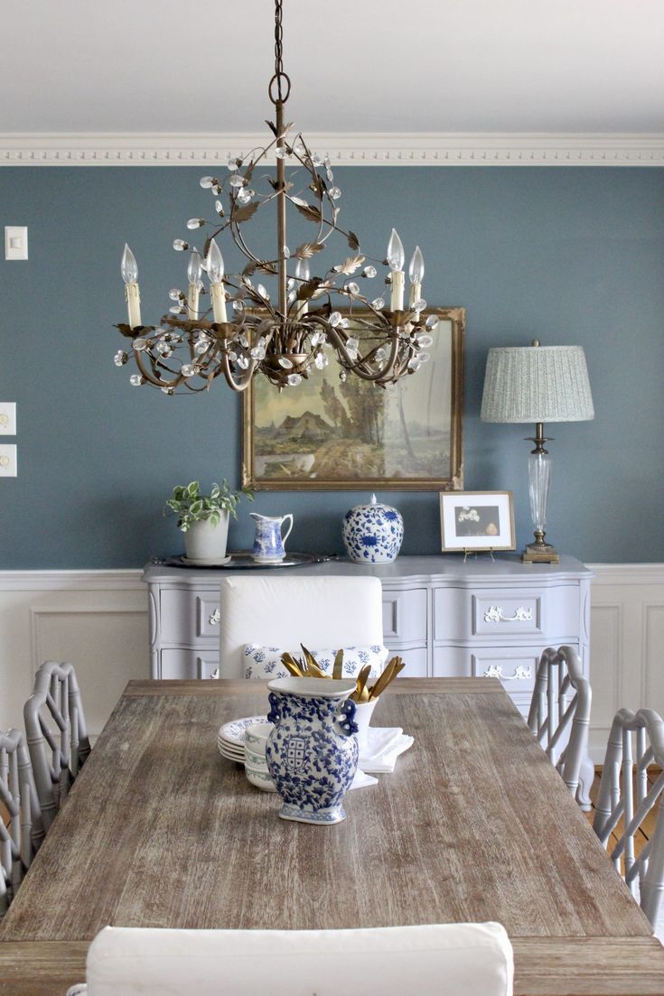 a dining room table with chairs and a chandelier hanging from the ceiling over it