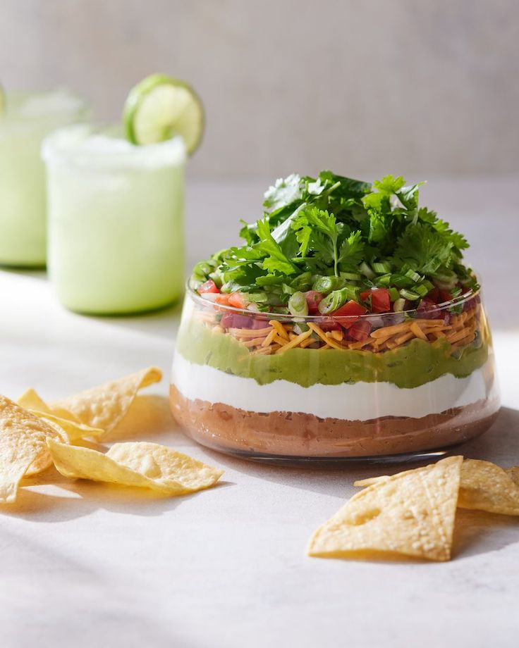 an image of food in a bowl with chips and limes on the side for garnish