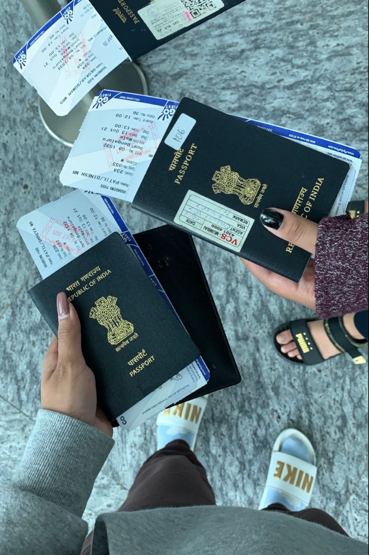 two people are holding their passport while standing on the floor