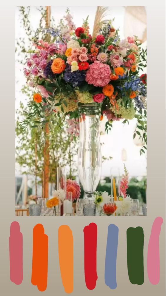 a vase filled with lots of colorful flowers on top of a table next to candles