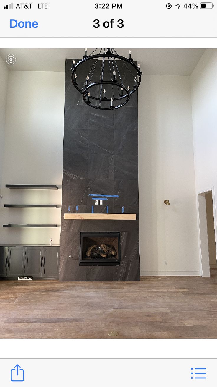 an empty living room with a fire place in the center and a chandelier hanging from the ceiling