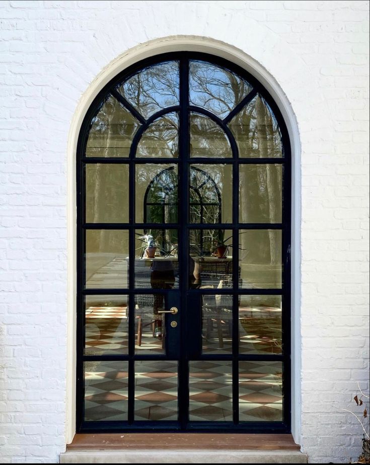 an arched glass door in front of a white brick building