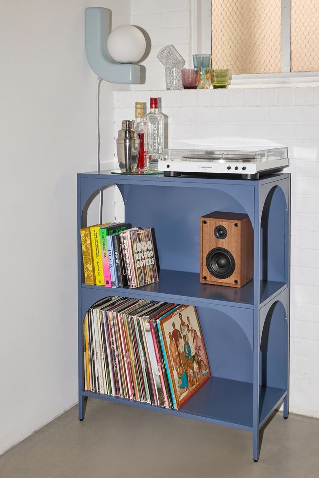 a blue shelf with some records and a stereo on it in front of a mirror