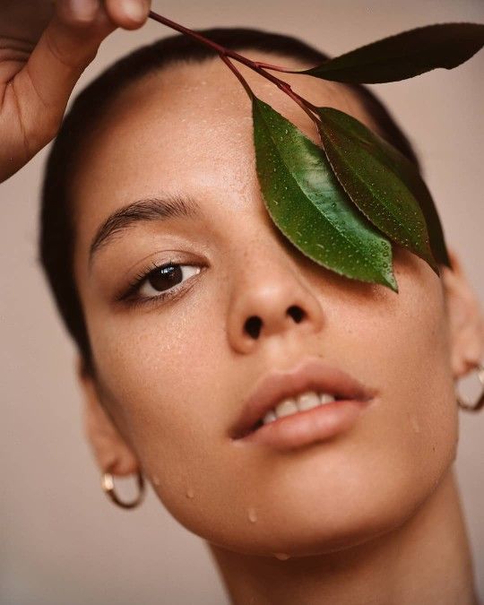 a woman holding a green leaf over her face