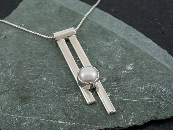 Rosario set a genuine pearl in an edgy vertical setting that fits right in with our Pendulum collection. Delivered on an 18" sterling silver faceted bolitas chain (pictured). Weight: 4 grams. Contemporary Gift Jewelry Long Drop, Modern Pearl Pendant Jewelry For Anniversary, Modern Silver Jewelry With Pearl Drop, Modern Sterling Silver Jewelry With Pearl Pendant, Modern Silver Pearl Necklace With Pearl Drop, Modern Silver Pearl Necklace For Formal Occasions, Modern Silver Pearl Necklace For Formal Events, Modern Pearl Drop Pendant Necklace, Contemporary Drop Style Jewelry For Gifts