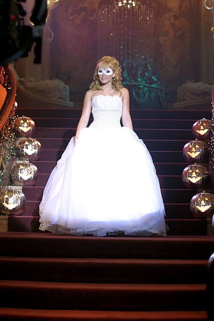 a woman in a white dress is standing on some stairs with balls around her head