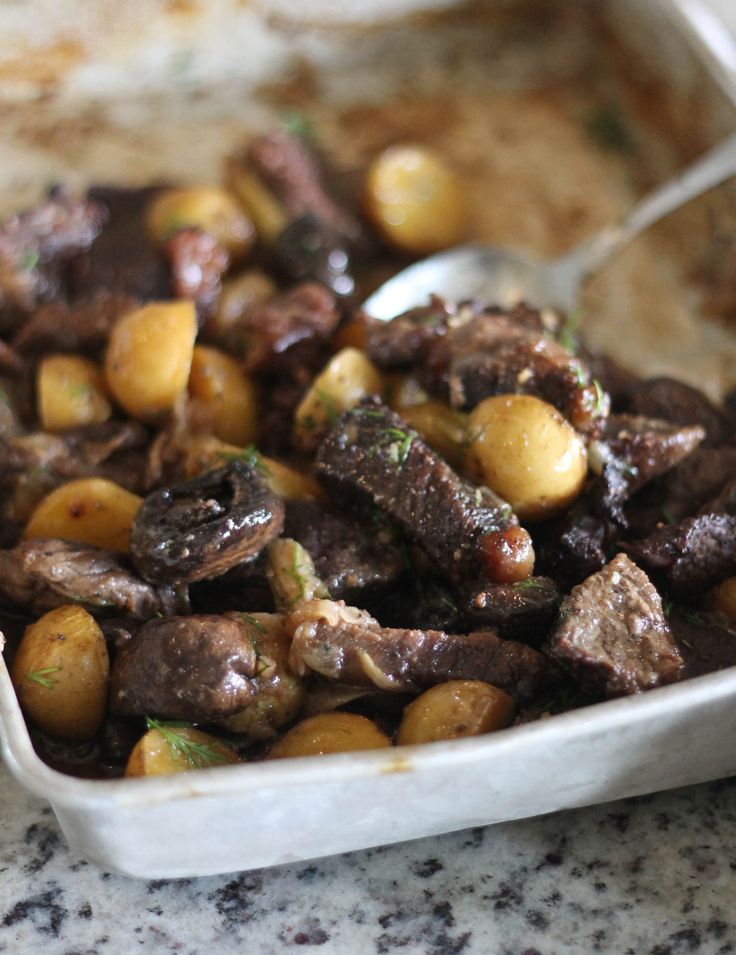 a bowl filled with meat and potatoes on top of a table