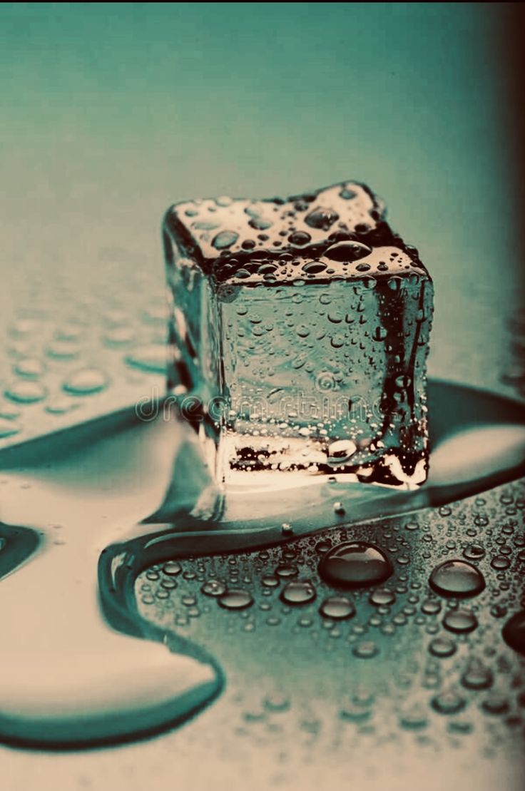 an ice cube sitting on top of a table next to water droplets and spoons