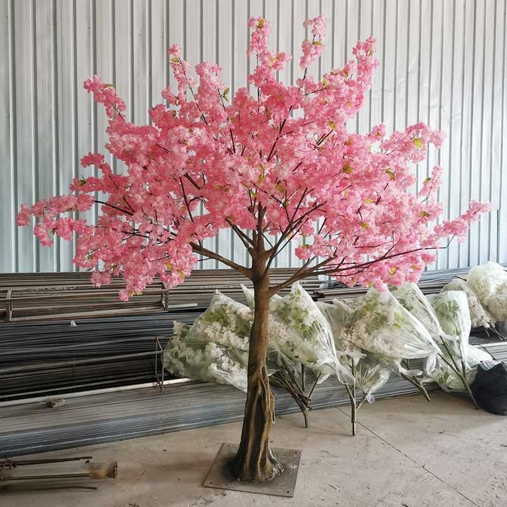 a tree with pink flowers is in the middle of a room filled with other items