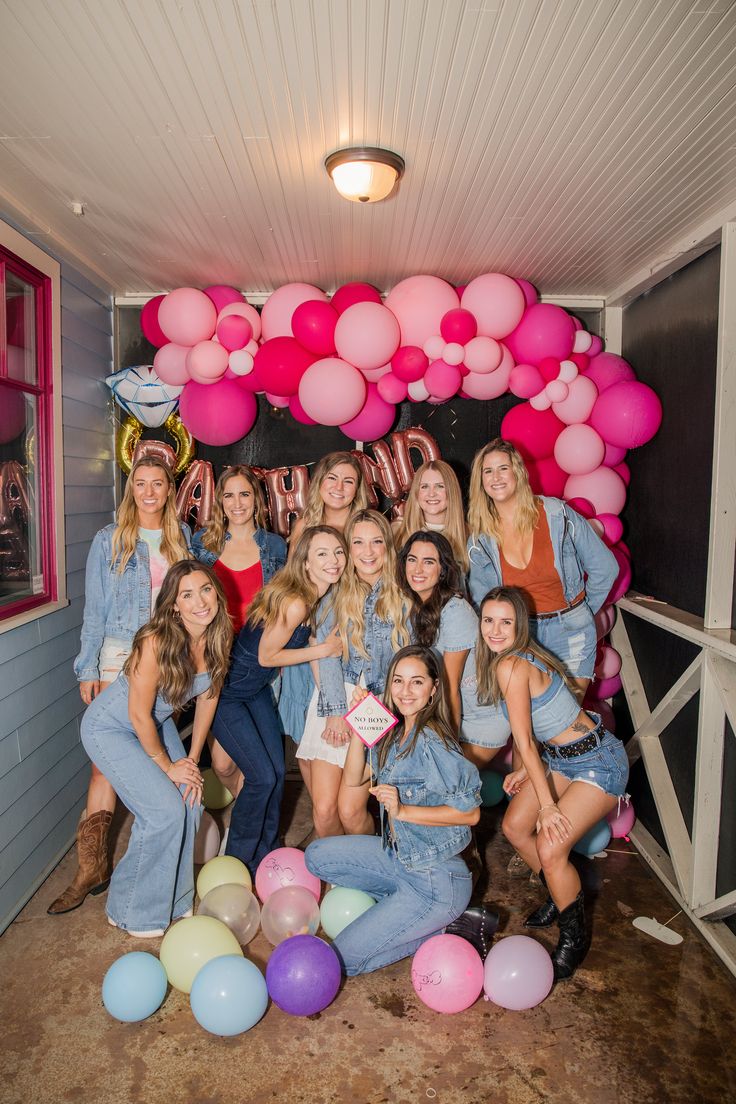 a group of women standing next to each other in front of a bunch of balloons