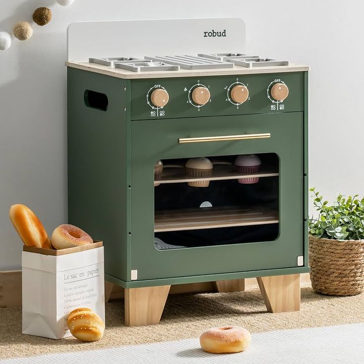 a green oven sitting on top of a rug next to donuts and a cupcake