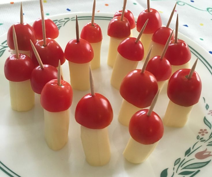 small appetizers with cherries on toothpicks are arranged on a plate