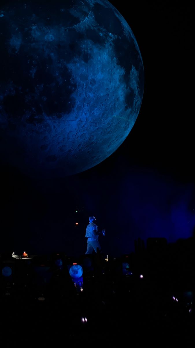 a person standing in front of a large blue moon