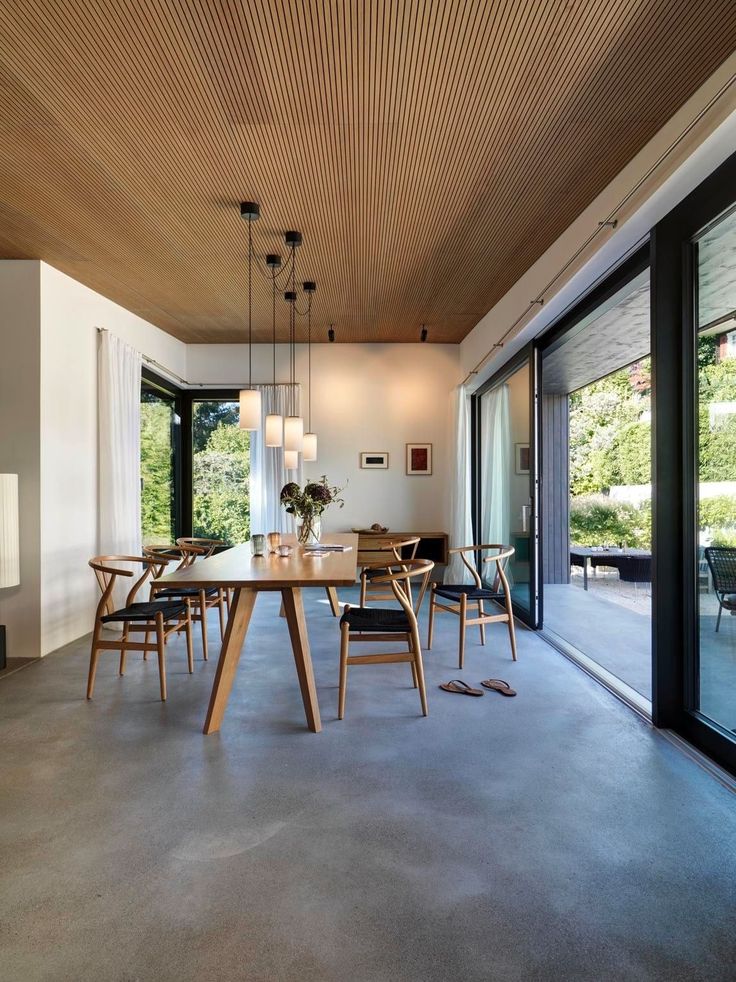 a dining room table surrounded by chairs and windows with sliding glass doors to the outside