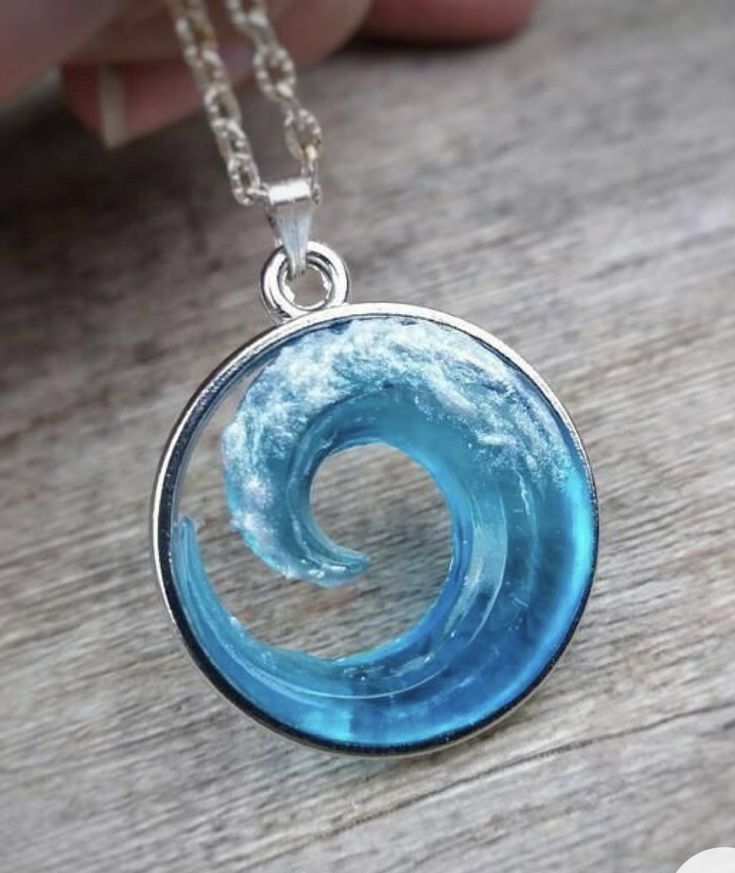 a handmade glass pendant with a blue wave in the center on a wooden table