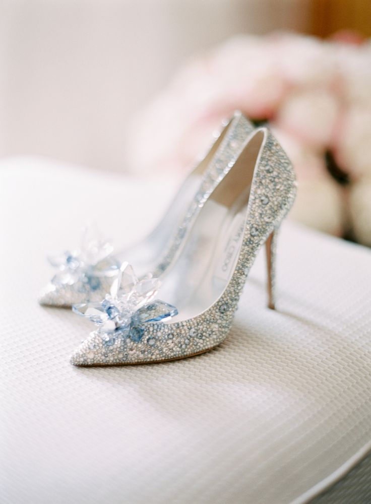 a pair of silver high heel shoes sitting on top of a white suitcase with flowers