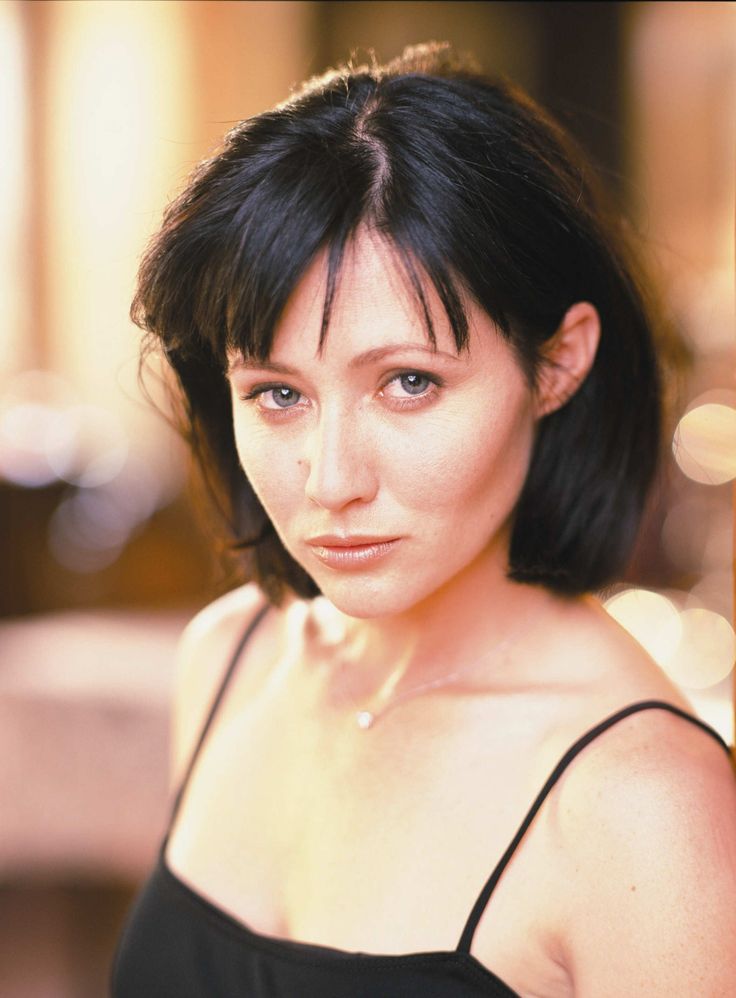 a close up of a person wearing a black shirt and posing for a photo with her hand on her hip