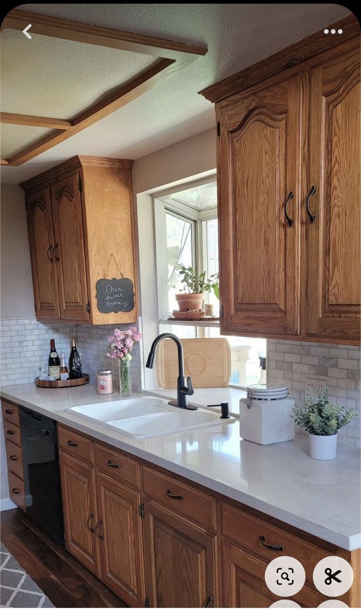 a large kitchen with wooden cabinets and white counter tops is pictured in this image, the sink has a black faucet on it's side