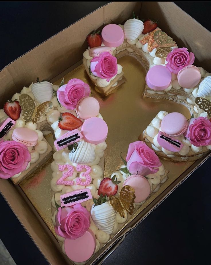 a heart shaped cake in a box with pink frosting and roses on it's sides