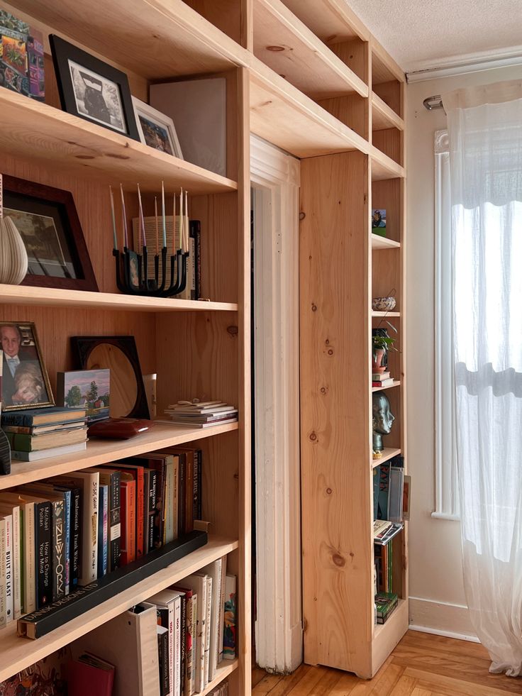 a book shelf filled with books next to a window