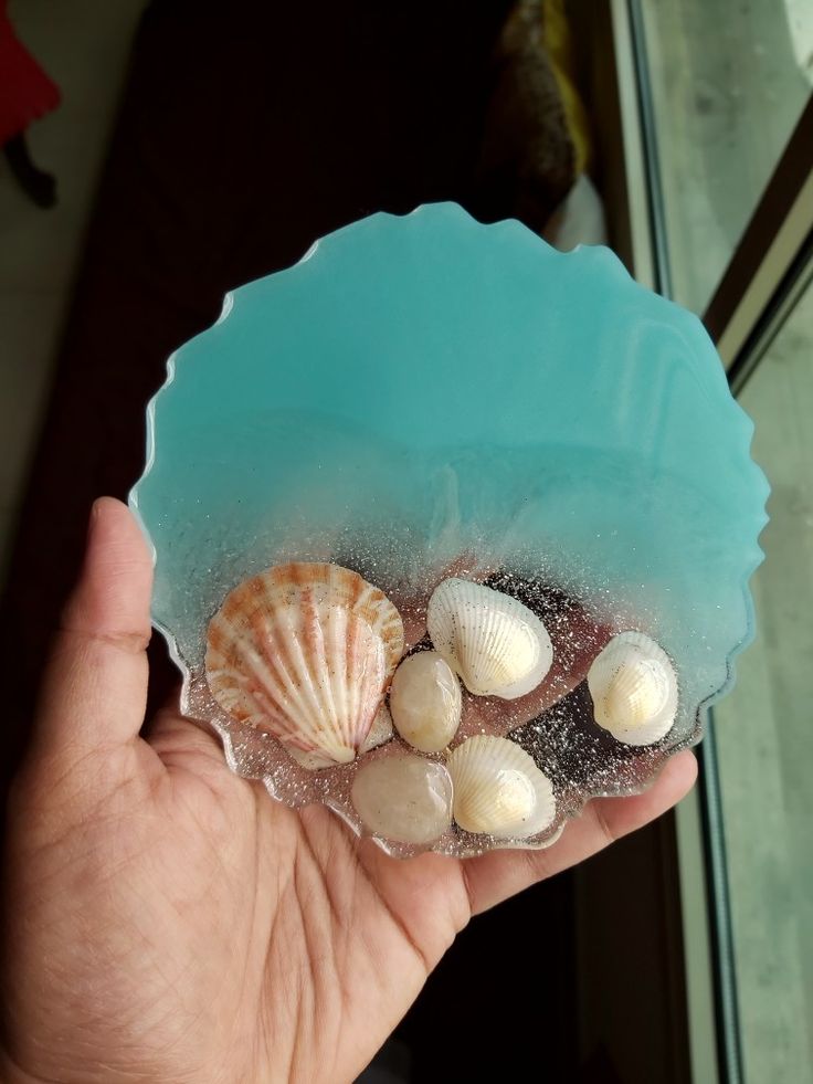 a hand holding a bowl filled with sea shells