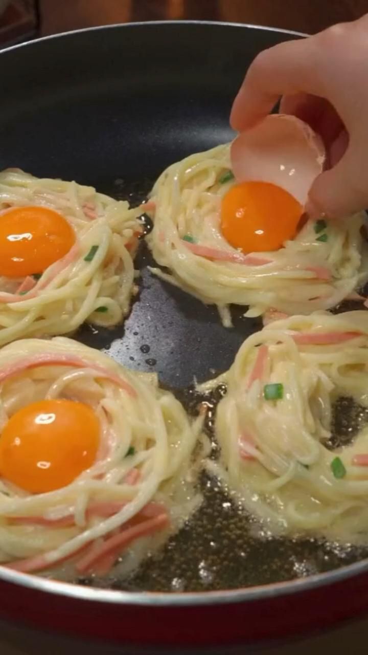 someone is frying eggs on top of spaghetti in a pan