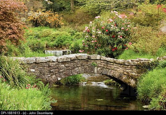 a stone bridge over a stream in a lush green field