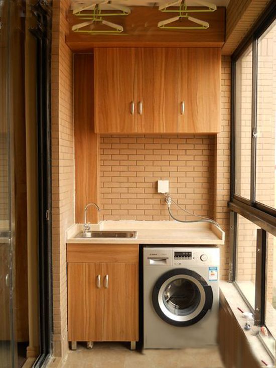 a washer and dryer sitting in a small room next to a window with wooden cabinets