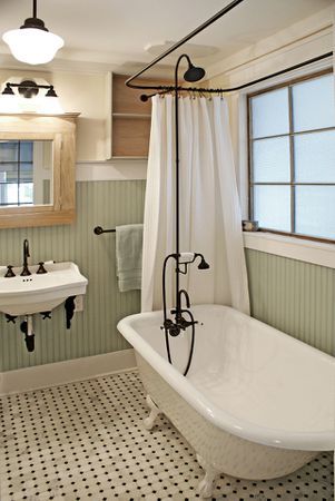 a white bath tub sitting next to a sink in a bathroom with green walls and black and white flooring