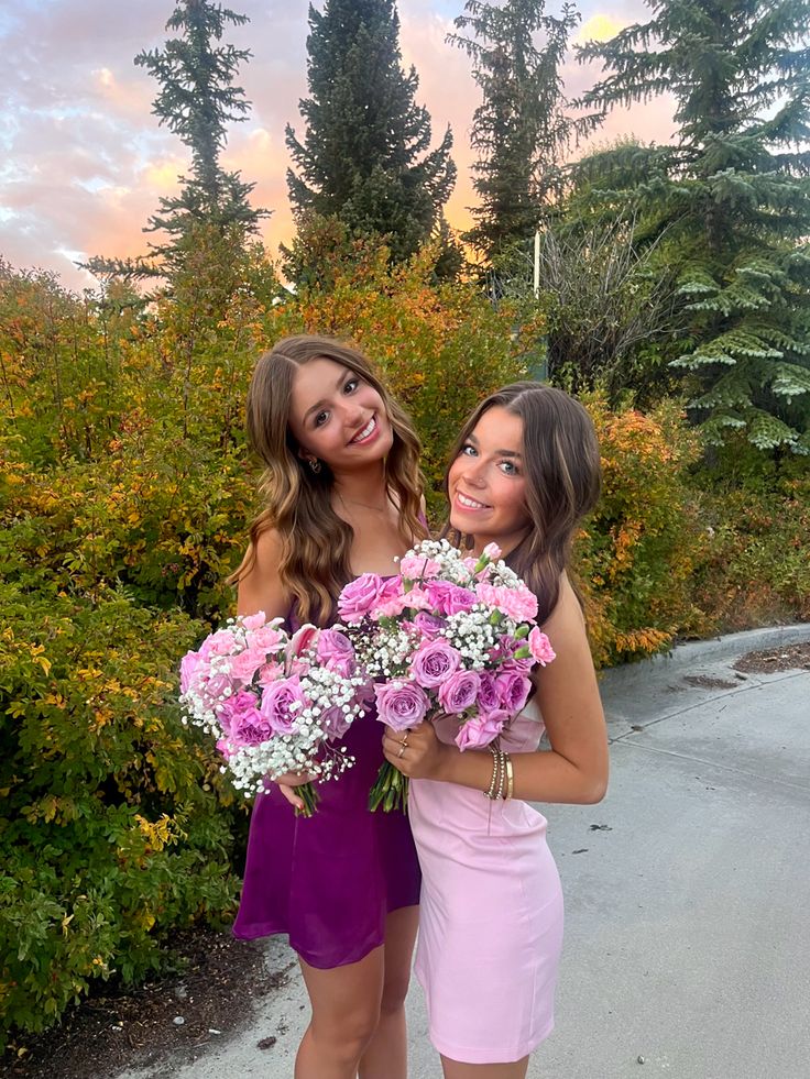 two beautiful young women standing next to each other holding bouquets of pink and white flowers