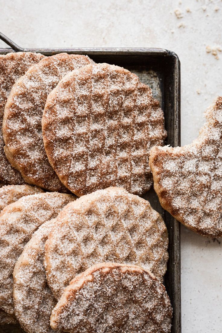 several cookies with powdered sugar on top are in a baking pan, ready to be eaten