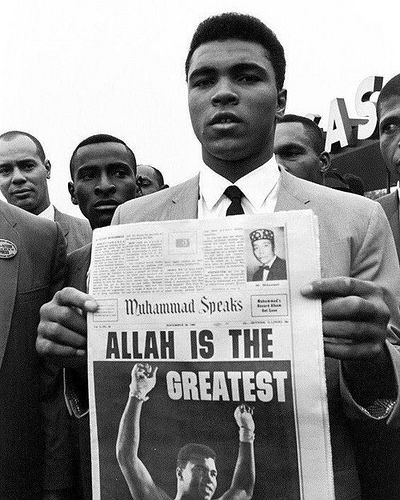 a black and white photo of a man holding up a news paper with the words alah is the greatest